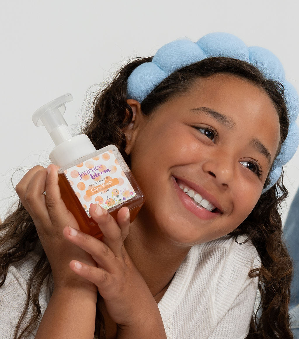Smiling tween holding a gentle foaming face cleanser