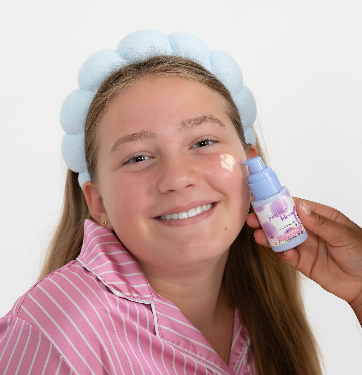 Smiling tween applying a lightweight moisturizer