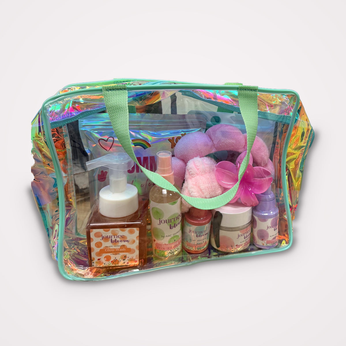 Journee Bloom Ultimate Glow Kit in an iridescent glow bag with glow wash, serum, cream, scrub, lip balm, patches, and headband set